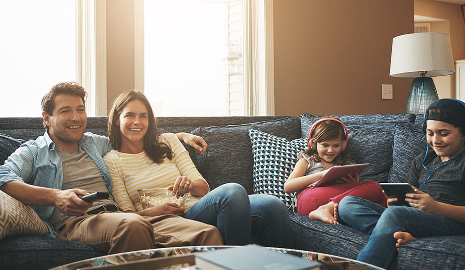 Familie schaut Fernsehen, während die Kinder ihre Tablets benutzen