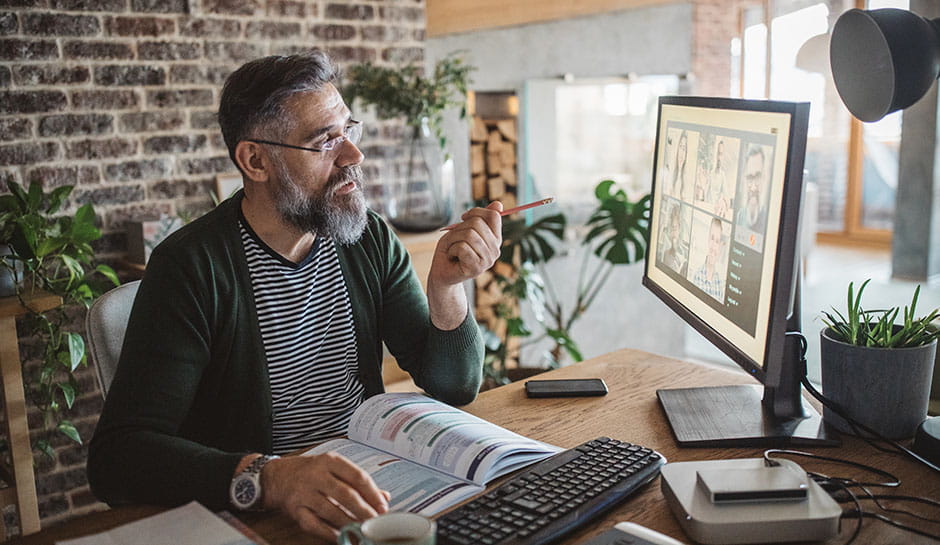 Älterer Herr nimmt im Homeoffice an einer Videokonferenz teil